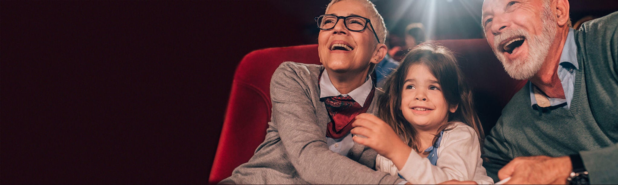 Grandparents and granddaughter watching a movie.