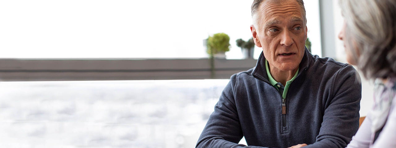 Middle-aged couple outdoors talking in physician's office.