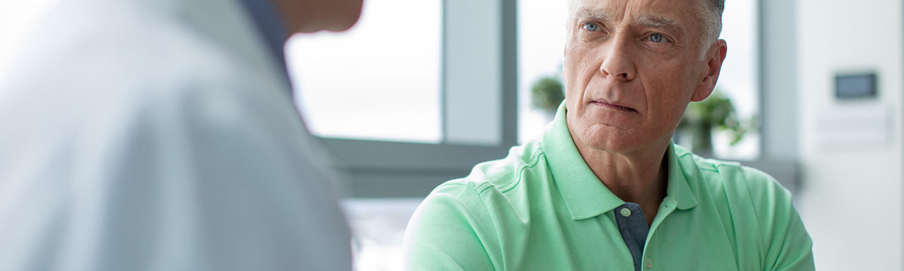 Man in green polo listening to physician.